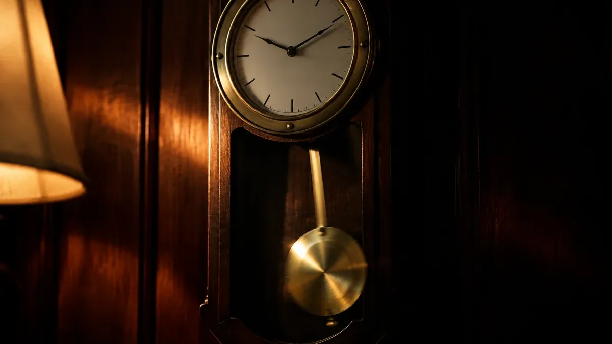 Messingpendel einer Wanduhr mitten im Schwung vor dunkler Holzwand