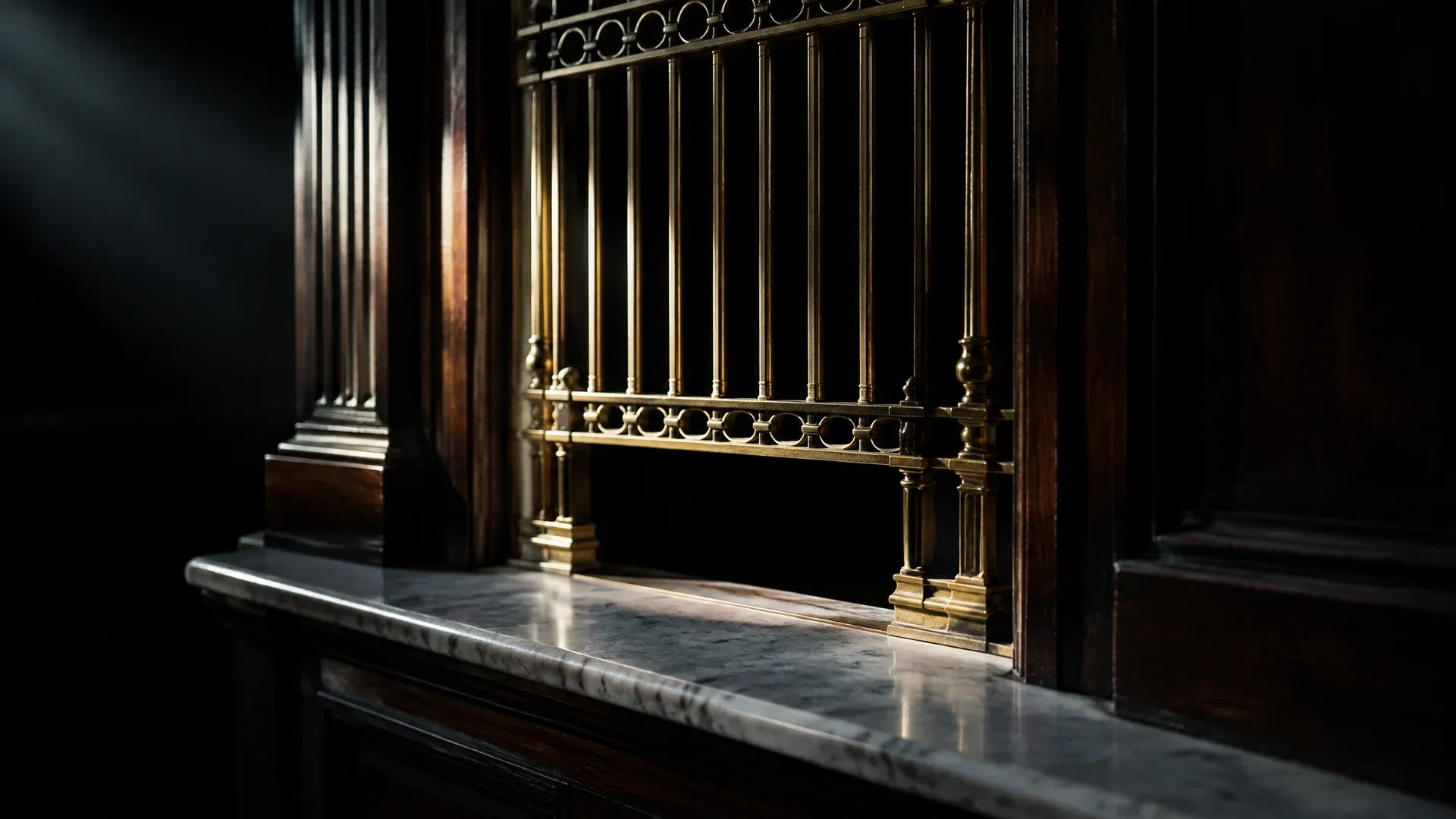 Alter Bankschalter aus dunklem Holz mit vergittertem Messingfenster und leerer Marmorablage im Seitenlicht