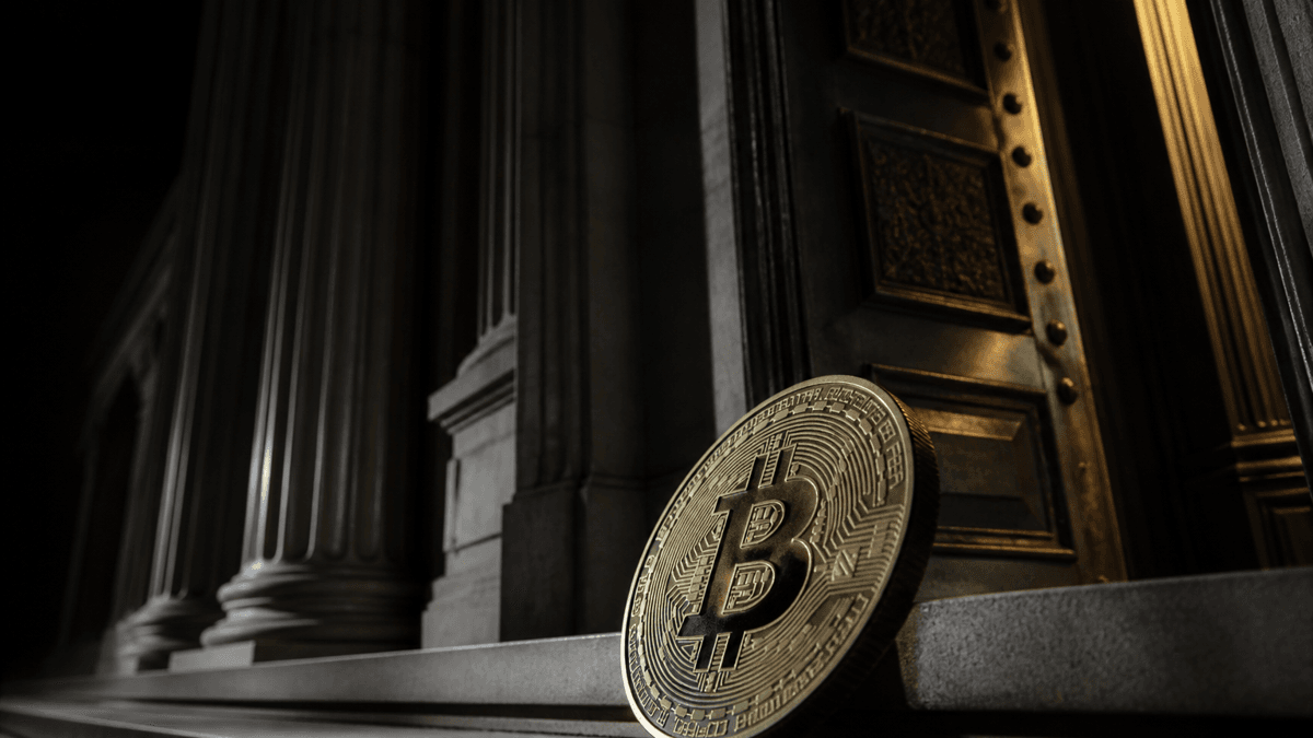 Nächtliches klassizistisches Behördengebäude mit Säulen und halb geschlossenem Bronzeportal, davor auf der Treppe eine große Bitcoin-Münze