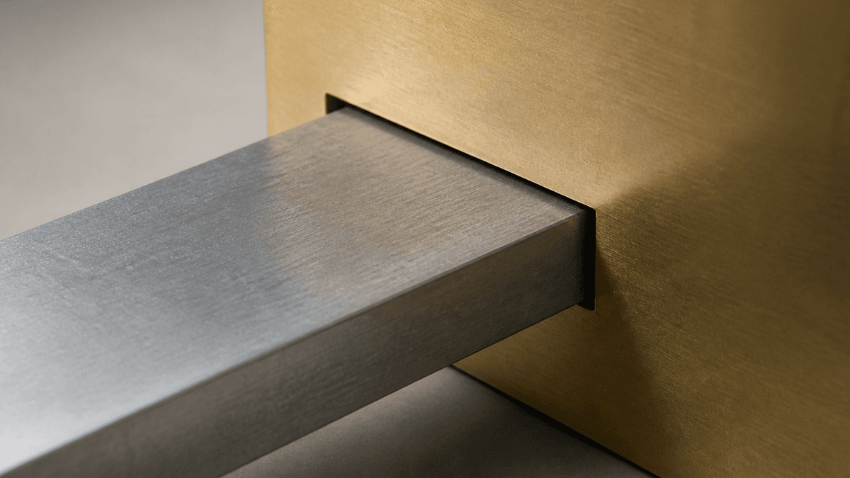 Ein flacher Metallriegel zur Haelfte in eine passgenaue Aussparung einer Messingplatte geschoben