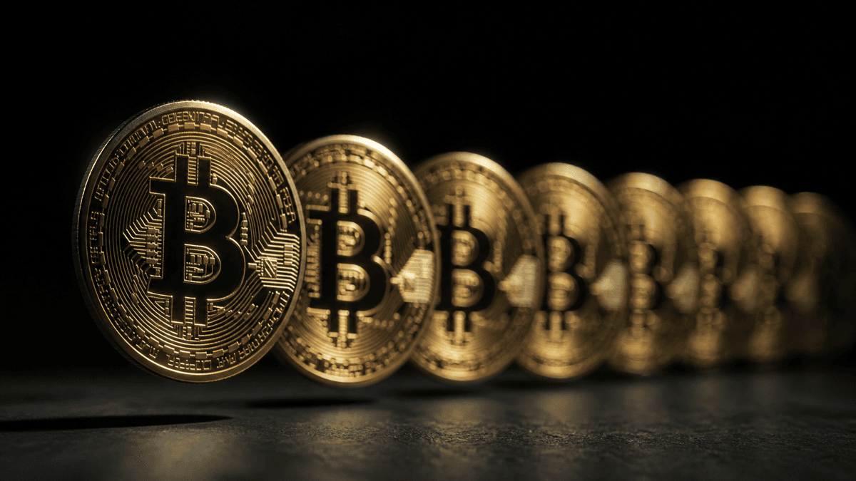 Eight physical Bitcoin coins lined up like a queue, the front one slightly raised, those behind it out of focus