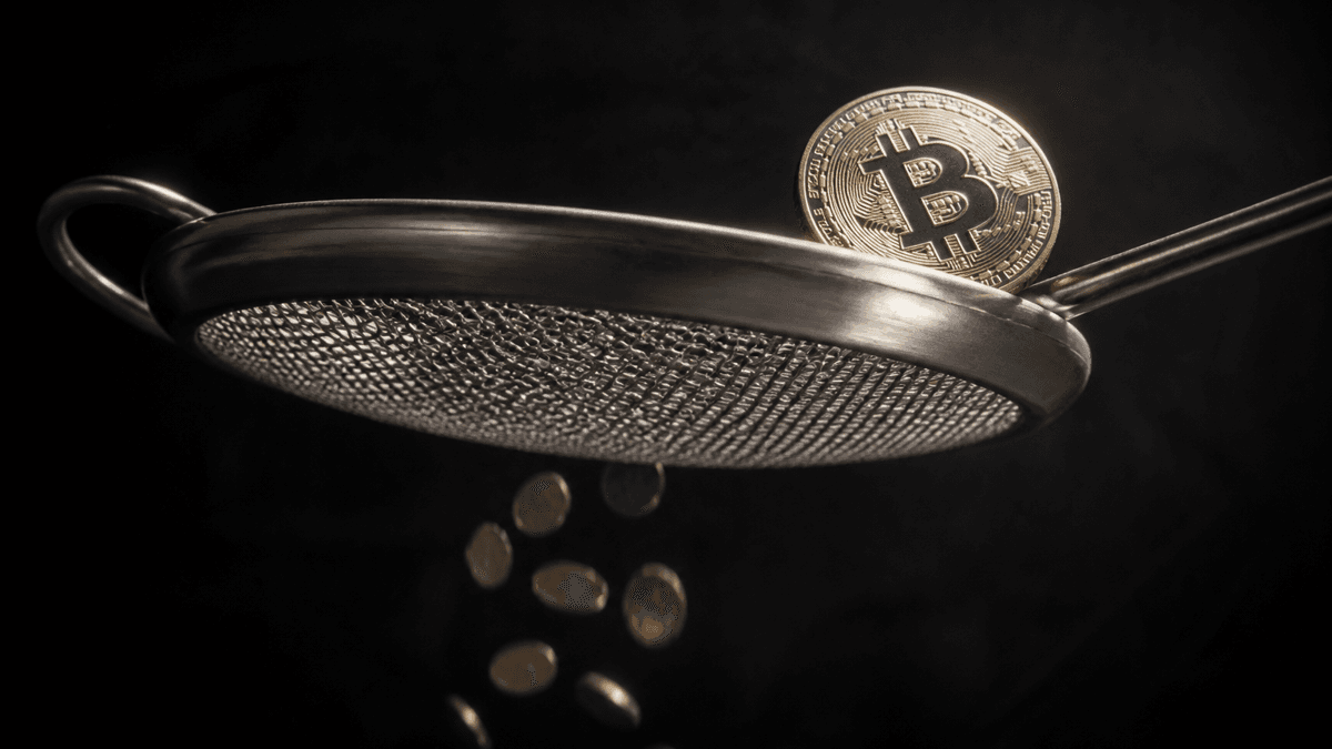 Sieb aus gebuerstetem Stahl, durch dessen Maschen kleine Muenzen fallen, waehrend eine grosse Muenze mit eingepraegtem Bitcoin-Zeichen auf dem Rand liegen bleibt