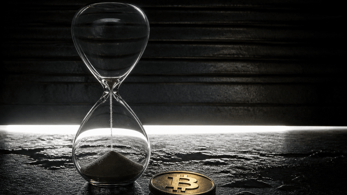 Eine fast leergelaufene Sanduhr aus Glas auf einer nassen dunklen Steinplatte, daneben eine goldene Muenze mit Bitcoin-Zeichen, im Hintergrund ein schmaler Lichtspalt unter einer herabfahrenden Stahlklappe.