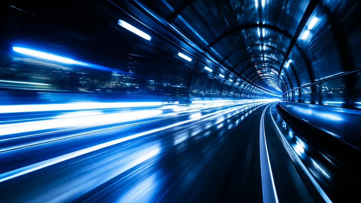 Lichtspuren rasen durch einen dunklen Glastunnel
