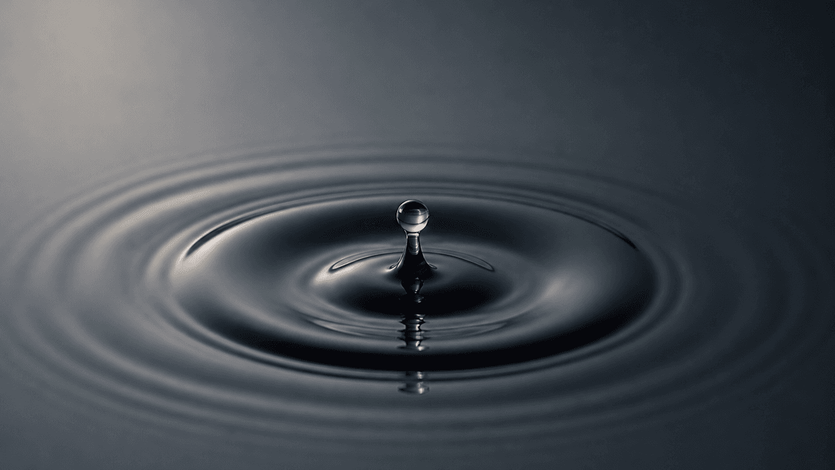 Ein einzelner Wassertropfen im Moment des Aufpralls auf eine dunkle Wasserfläche mit konzentrischen Ringen